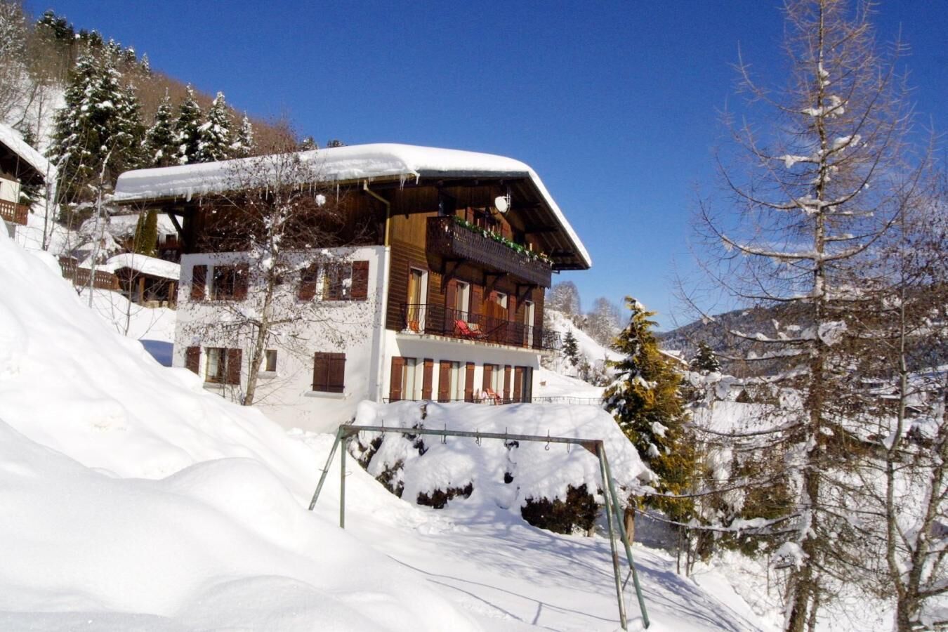 Un edificio in stile chalet con facciata in legno, numerosi balconi e tetto innevato.