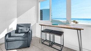 Una habitación moderna con un sofá gris, un escritorio de madera y vistas al océano.