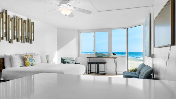 Un dormitorio moderno con una cama grande, un escritorio y vistas al océano.