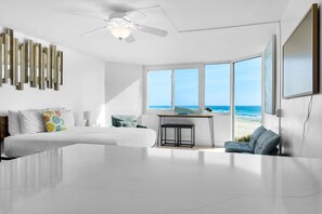Un dormitorio moderno con una cama grande, un escritorio y vistas al océano.