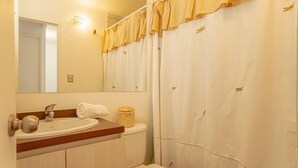 A bathroom with a sink, mirror, and shower curtain. - Golden Pucon 3BR (Pucon)