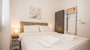 Une chambre d’hôtel comprenant un lit, une table de chevet avec une lampe, une armoire et un porte-serviettes.