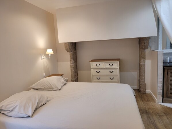 A bedroom with a bed, a nightstand, a dresser, and a wall-mounted lamp. - Manoir de fenayrol (Coeur-de-Causse)