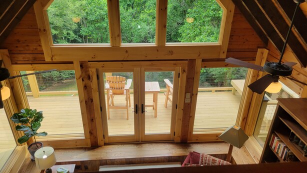 A wooden cabin with a large sliding glass door leading to an outdoor deck with a table and chairs. - Charming home in Seven Devils. Close access to tubing, ziplining, & hiking. (Seven Devils)