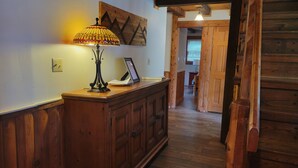 A wooden hallway with a desk and lamp, a framed certificate, and a wooden door leading to another room. - Charming home in Seven Devils. Close access to tubing, ziplining, & hiking. (Seven Devils)
