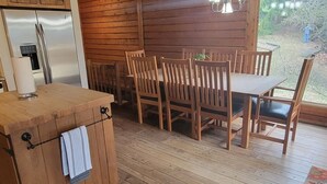 A rustic wooden interior with a dining area, wooden ceiling beams, and a view of the outdoors. - Charming home in Seven Devils. Close access to tubing, ziplining, & hiking. (Seven Devils)