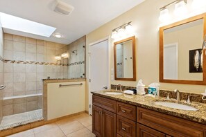 Un baño moderno con cabina de ducha, tocador de granito y un espejo grande.