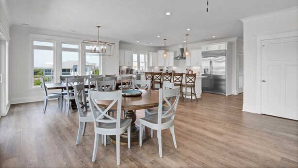A spacious kitchen with white cabinets, a stainless steel refrigerator, and a ceiling fan.