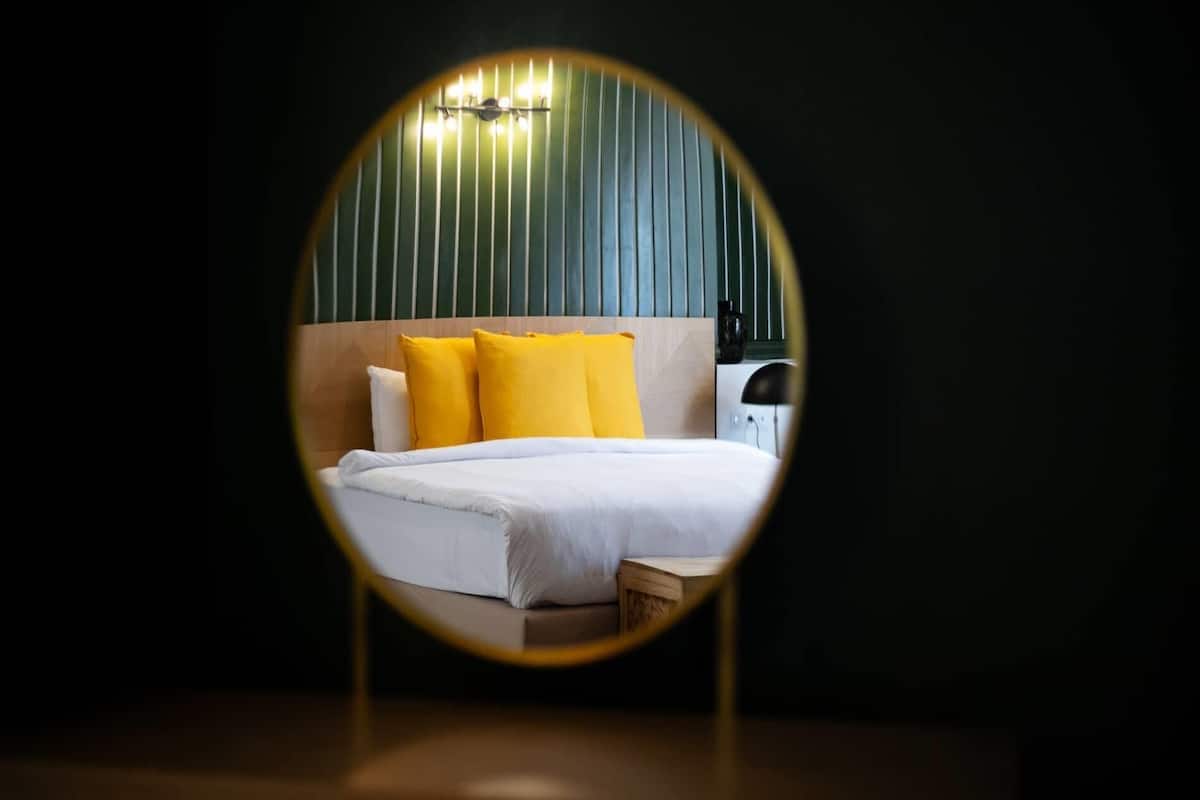 A circular view of a hotel room with a bed, pillows, and a nightstand.