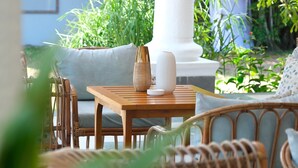 A wooden table with two vases and a wicker chair in a garden setting. - Le Palais d'Akwa (Abidjan)
