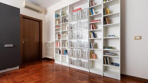A room with a wooden door, a radiator, and a white bookshelf filled with books. - Italianway Easy - Sismondi 74 (Milan)