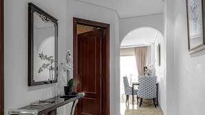A hallway with a marble floor, a wooden door, a console table with a mirror, and a dining area with patterned chairs. - Ocean View Apartment in Golf del Sur (Golf del Sur)