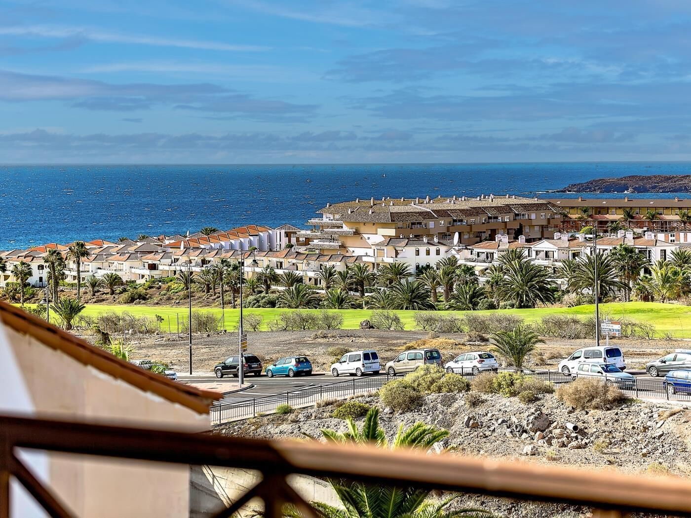A coastal residential area with a row of houses, a parking lot, and a view of the sea.