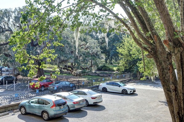 Um estacionamento com vários carros, rodeado por árvores e uma cerca.