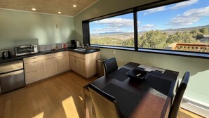 A modern kitchen with a built-in oven, a sink, and a dining area with a table and chairs.