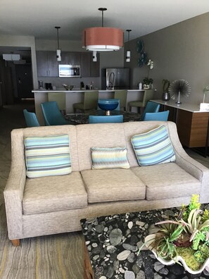 Relax in this stylish living room with a comfortable sofa, modern kitchen, and dining area.