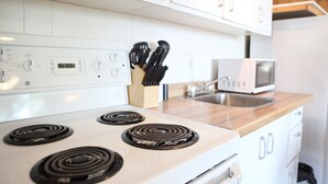 A kitchen with a white stove, a microwave, and a wooden countertop. - "Shore Thing" Sunset Views (Seven Sisters Falls)