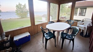 A covered patio with a table and chairs, overlooking a body of water and a grassy area. - "Shore Thing" Sunset Views (Seven Sisters Falls)