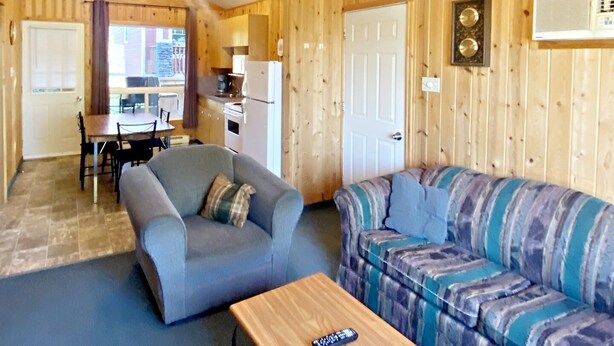 Un interior de cabaña acogedor con zona de comedor, sofá y mesa de madera.