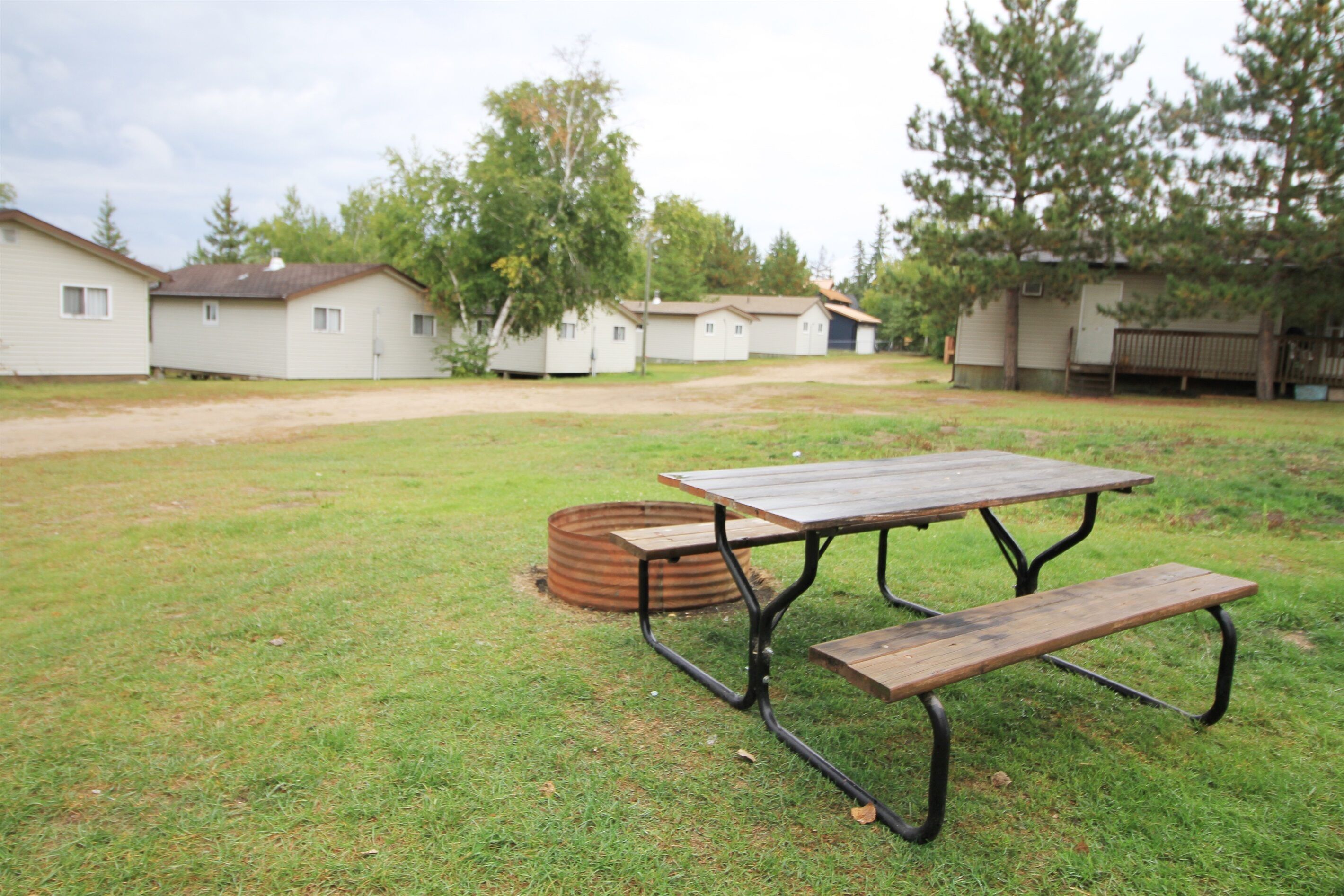A picnic table in a grassy area with portable cabins in the background.