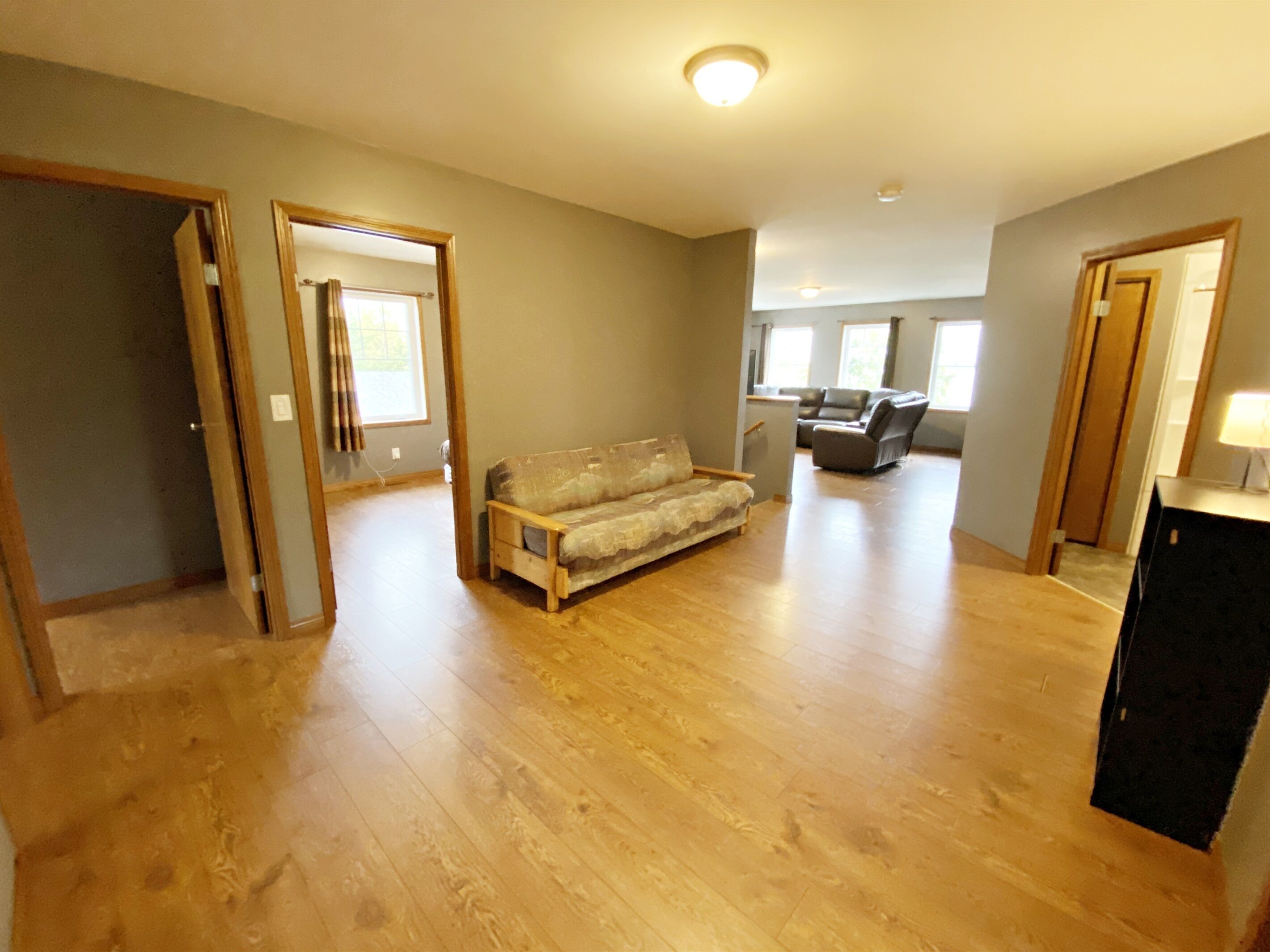 Een ruime woonkamer met houten vloeren, een bank en een eethoek met tafel en stoelen.