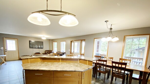A spacious kitchen with a large island, wooden cabinets, and a dining area with a table and chairs.