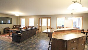 A spacious living area with a large dark-colored sofa, a wooden coffee table, and a kitchen island with drawers.