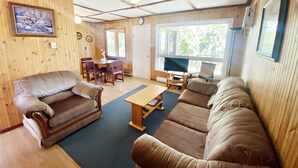 En hyggelig stue med træpaneler, en sofa, et spisebord og et fjernsyn.