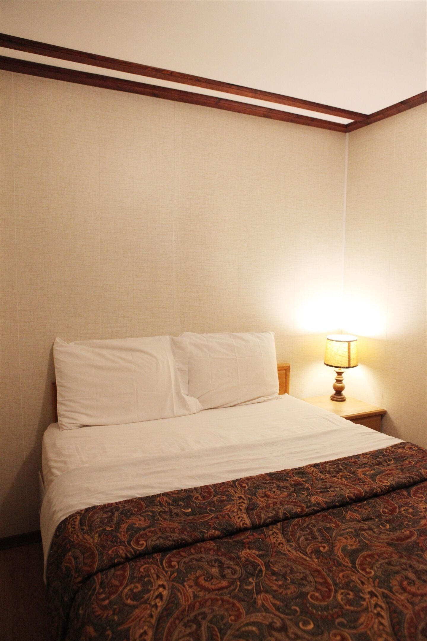 Een hotelkamer met een bed, nachtkastje en lamp.