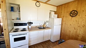 A small kitchen with white cabinets, a stove, a microwave, and a refrigerator. - "Lakeside Landing" Escape to paradise (Seven Sister Falls)