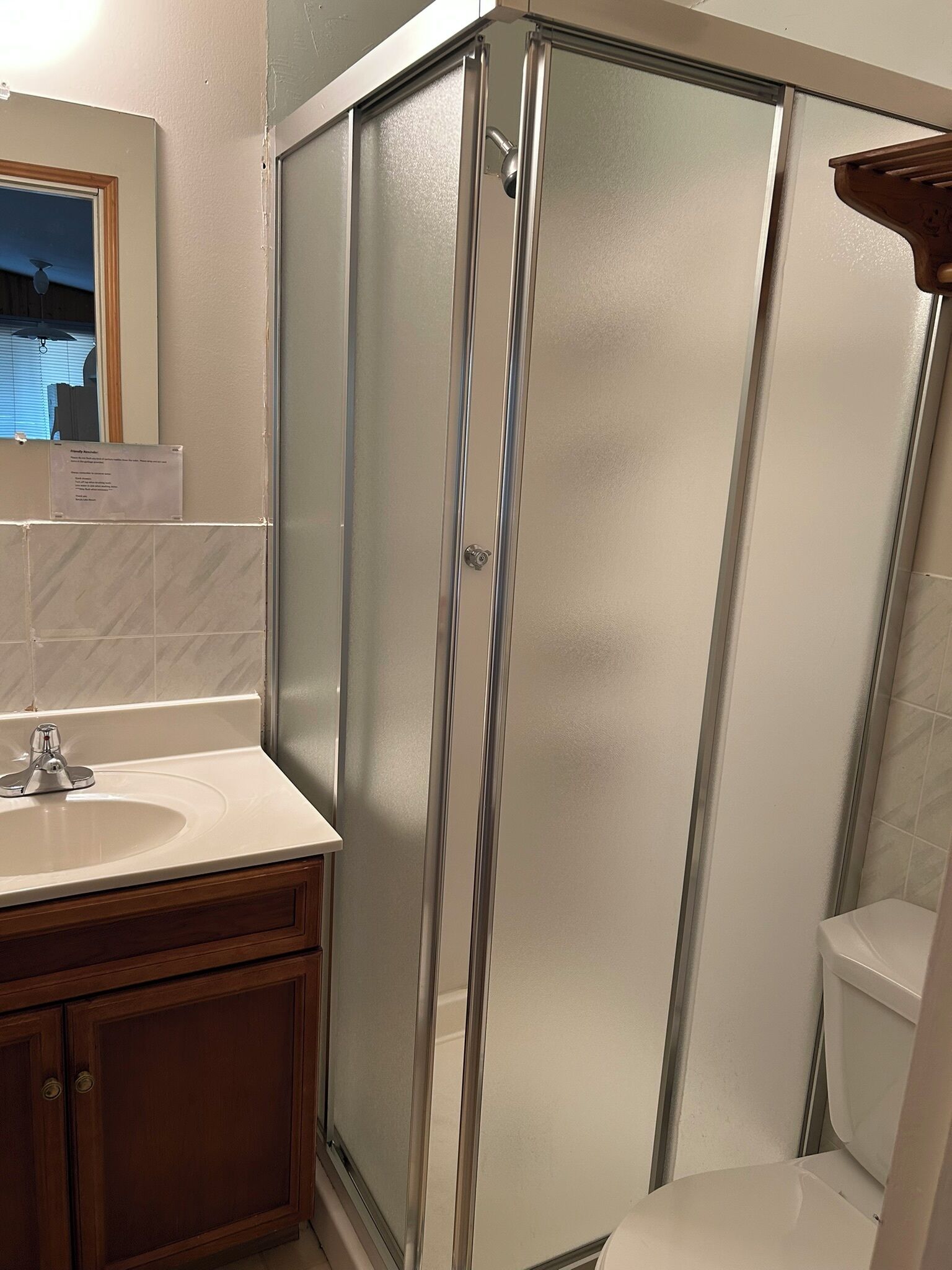A bathroom with a glass-enclosed shower, a sink with a mirror above it, and a toilet.