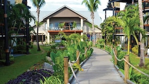 A resort with a wooden pathway leading to a building with balconies, surrounded by lush greenery and palm trees. - Fiji -Whyndham- Beachfront Resort- Denarau - 3 BR (Denarau Island)