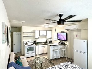 A compact living space with a kitchenette, a ceiling fan, a flat-screen TV, and a sofa. - B Casa Azul Minutes from Beach & Mall (North Palm Beach)