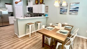 Une cuisine moderne avec des meubles blancs, un îlot central et des tabourets de bar.
