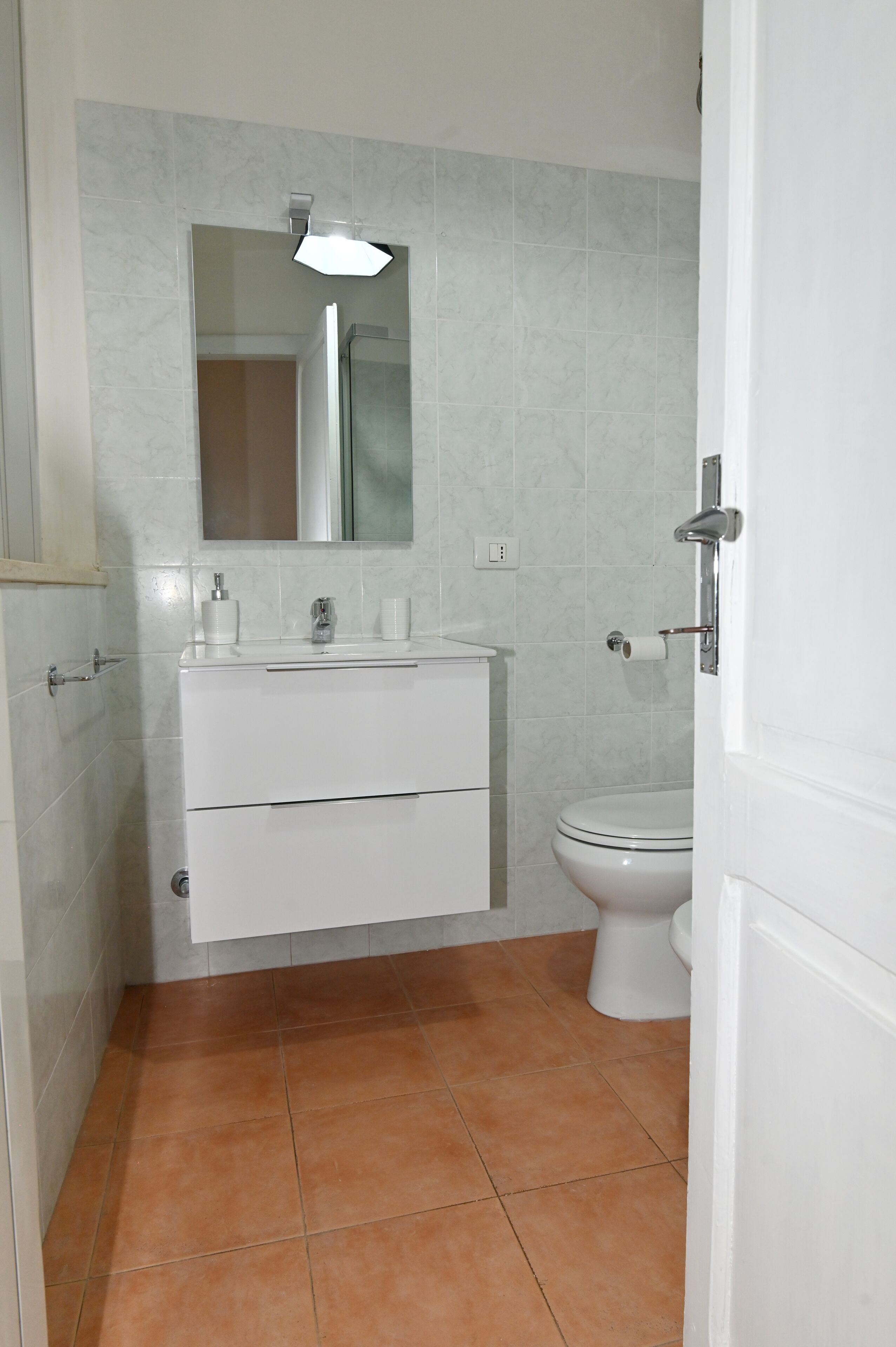 Ein Badezimmer mit weißem Waschbecken, Spiegel und Toilette.