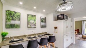 A modern kitchen with a long countertop, black bar stools, and white cabinets. - Riverfront Tennessee Retreat w/ Patio & Boat Ramp! (Elizabethton)