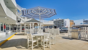 Ein überdachter Außenbereich mit Pavillon, weißen Stühlen und Grill.