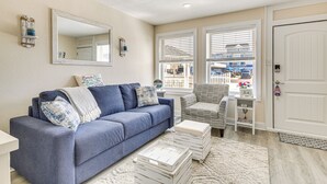 Ein Wohnzimmer mit einem blauen Sofa, einer weißen Bank und einem großen Fenster mit Jalousien.