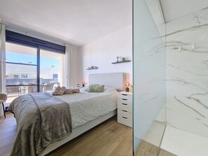 Relax in a spacious room with a large bed, bedside table, and balcony offering a view of the outdoor area.