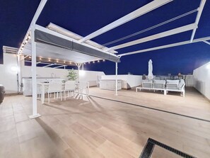 Relax on the rooftop terrace with a dining area, lounge seating, and a pergola for shade.