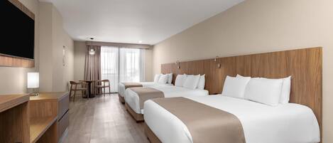 Habitación de hotel con dos camas, un escritorio, un televisor y una ventana con cortinas.
