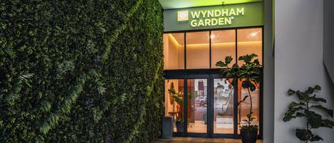 A modern building entrance with a green wall and a sign for 'Wyndham Garden'.