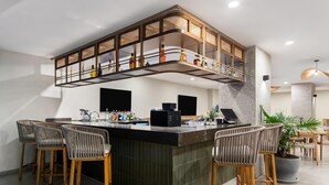 A modern bar area with a curved counter, wooden chairs, and a variety of bottles. - Wyndham Garden Mazatlan Marina (Mazatlán)