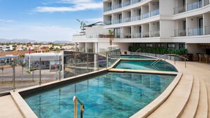 A modern hotel with a rooftop pool, multiple balconies, and a view of the surrounding town. - Wyndham Garden Mazatlan Marina (Mazatlán)