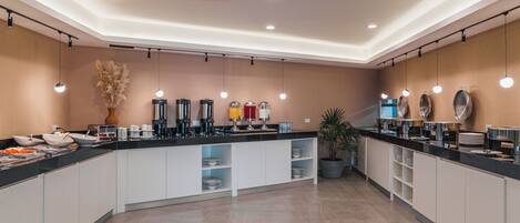 Uma cozinha moderna com ilha central, eletrodomésticos embutidos e iluminação pendente.