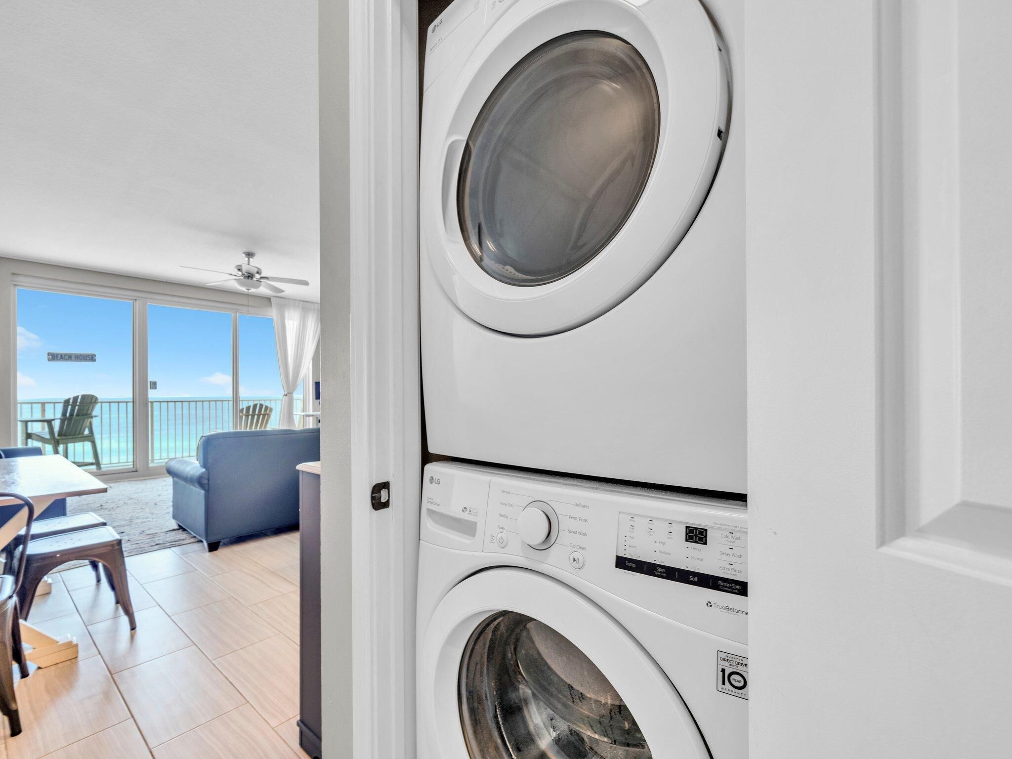 A laundry room with stacked washing machines, a balcony with a view, and a seating area with a table and chairs.