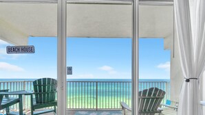 A balcony with a view of the beach, two green Adirondack chairs, and a sign reading "Beach House". - Shores of Panama 1002 (Panama City Beach)