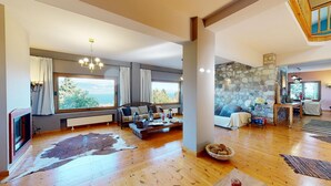 Amplia sala de estar con un ventanal grande, piso de madera y pared de piedra.
