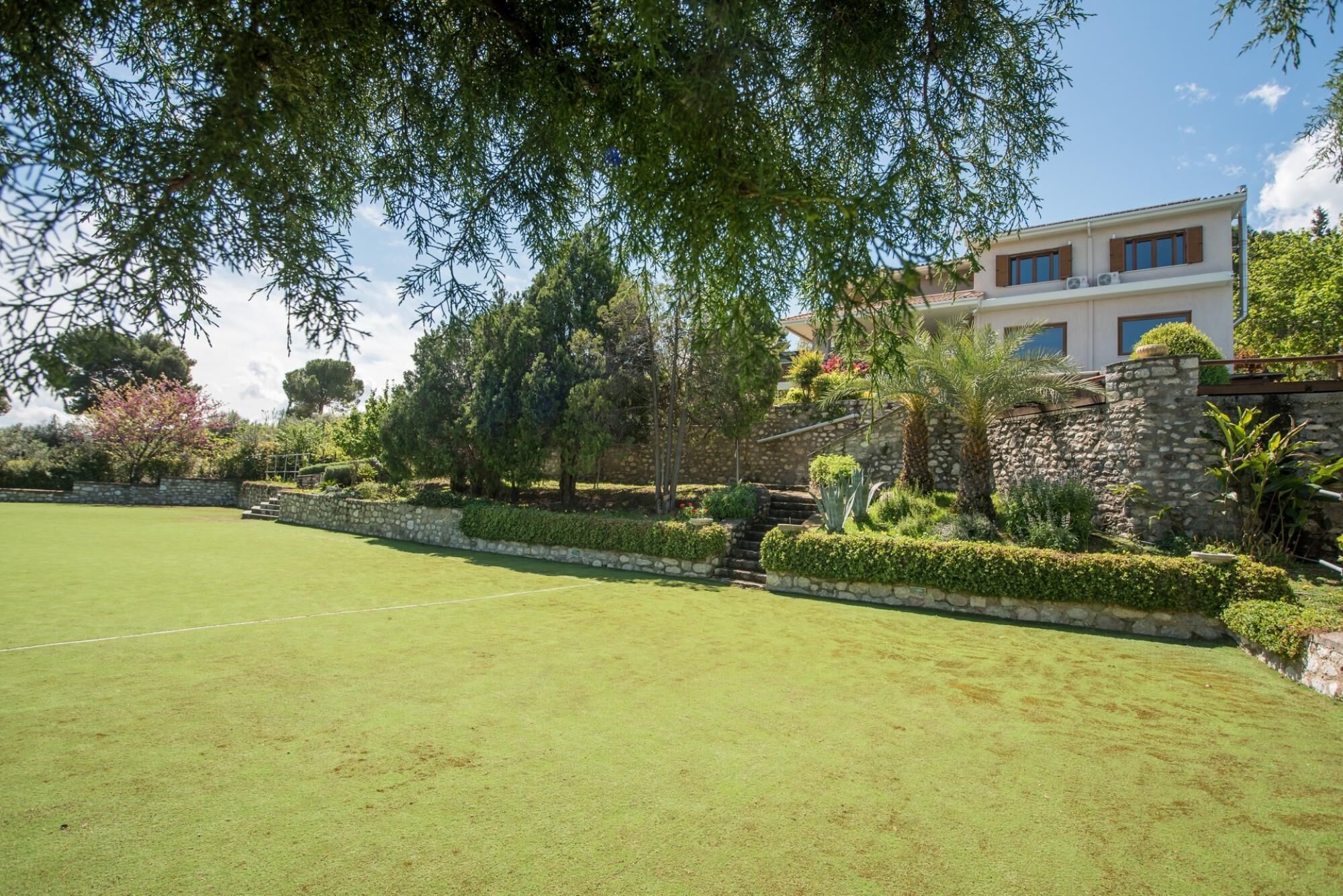 A well-maintained lawn with a stone wall and a building with multiple windows and a balcony.