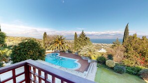 Relax by the pool surrounded by lush landscaping and scenic views of distant mountains and water.